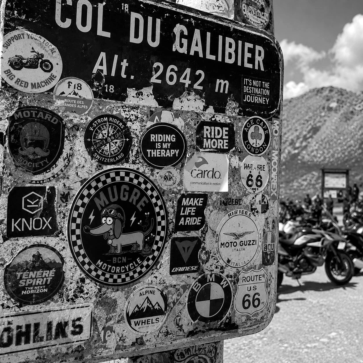 Pegatina de Mugre Motorcycle BCN en el poste del Col du Galibier, junto a otras marcas de moto