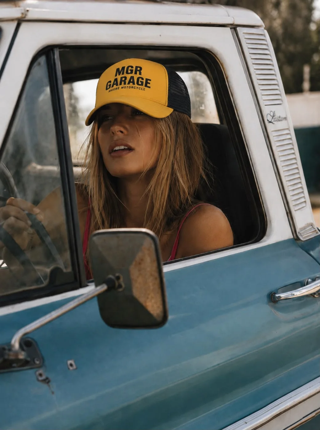 Persona con gorra MGR Garage al volante de una pickup clásica